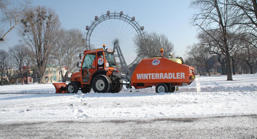 Winterradler : tracteur et sa remorque épandeuse de saumure lors de l’entretien d’une piste cyclable.
