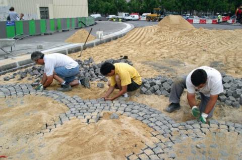 Réalisation d’un revêtement pavé en pose souple sur lit de sable.